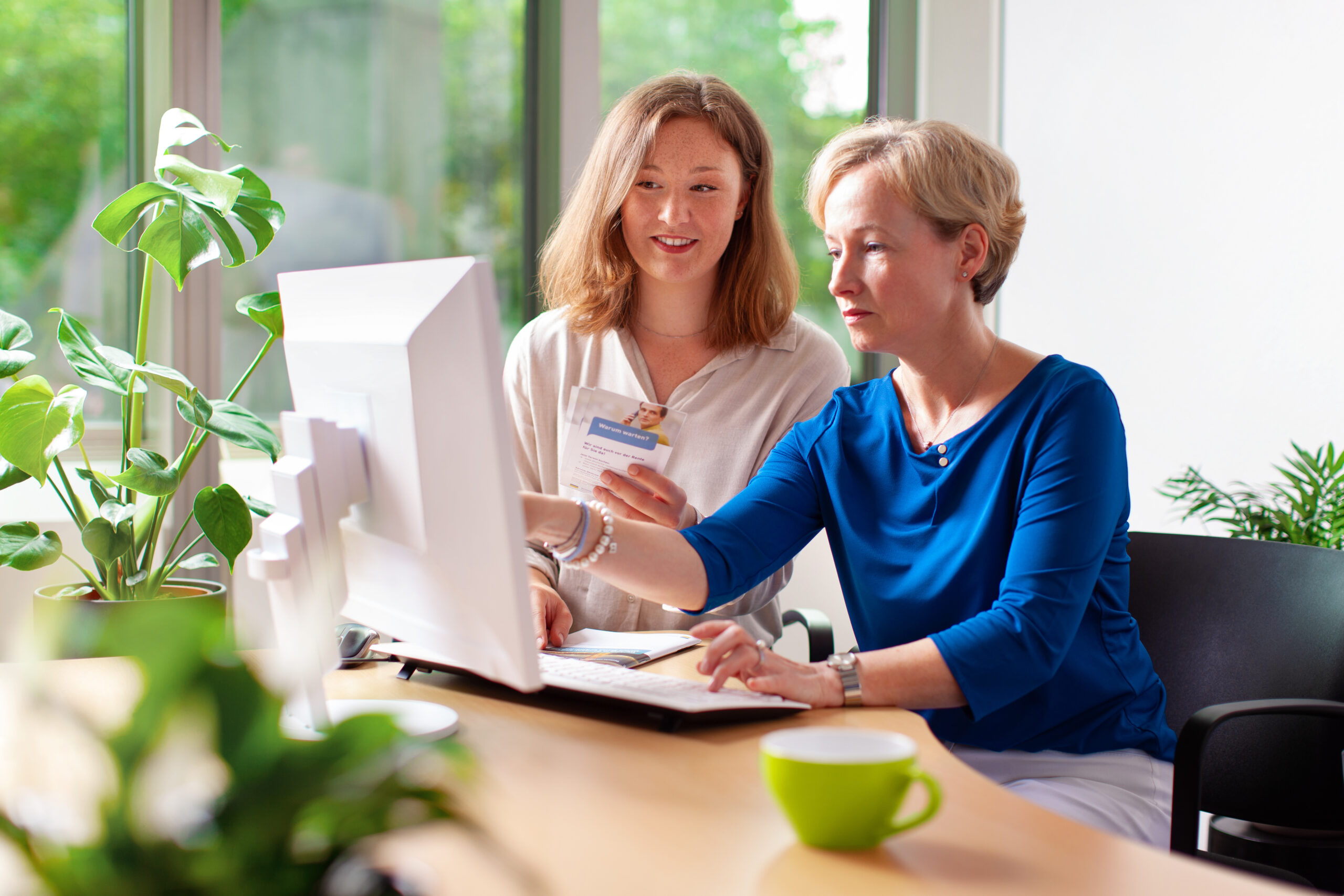 Zwei Mitarbeiterinnen schauen zusammen auf einen Computer.