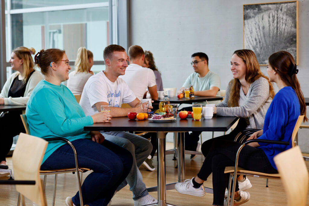 Eine freundliche Gruppe junger Mitarbeitender in der Kantine.