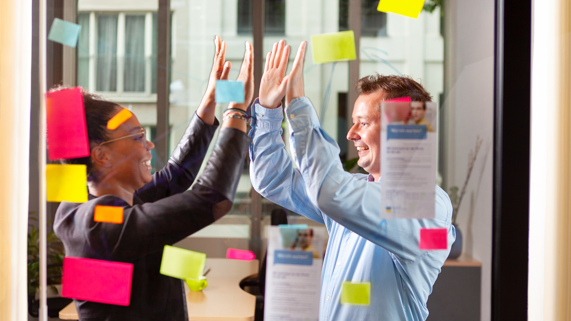 Mitarbeitende klatschen sich freudig ab.